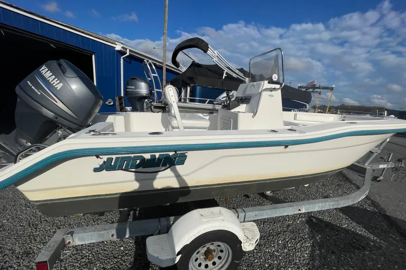 Slide: The Image of 2010 Sundance NX19 boat on trailer, Yamaha outboard, blue building background. - 5