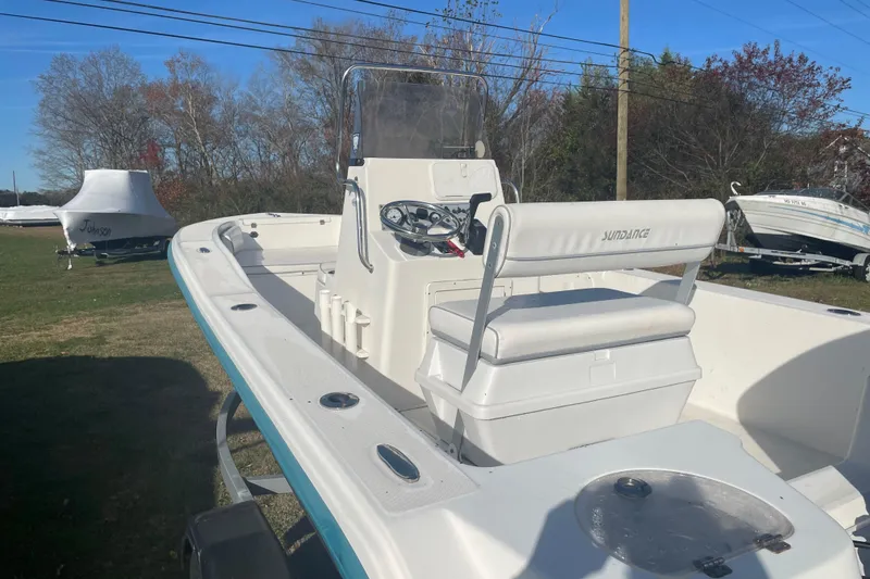 Slide: The Image of 2010 Sundance NX19 boat with white seating and console, parked outdoors. - 9