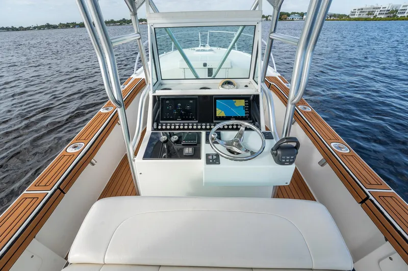 Slide: The Image of 2009 Bimini 24 Center Console boat interior with steering wheel and navigation system on water. - 17