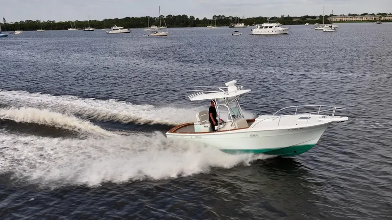 Slide: The Image of 2009 Bimini 24 Center Console boat cruising on a lake with other boats in the background. - 2