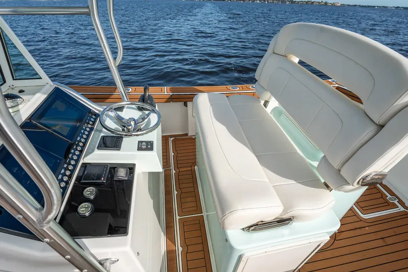 Slide: The Image of 2009 Bimini 24 Center Console boat interior with steering wheel and seating, on calm water. - 23