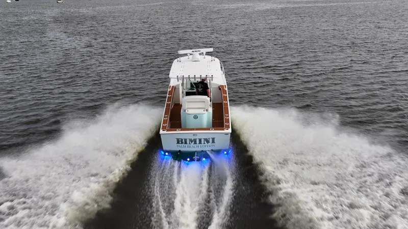 Slide: The Image of 2009 Bimini 24 Center Console boat cruising on open water with blue LED lights. - 6