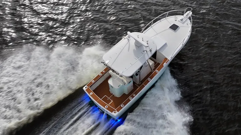 Slide: The Image of 2009 Bimini 24 Center Console boat cruising on water with blue underwater lights. - 7