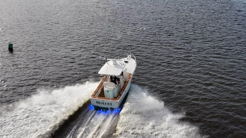 Slide: The Image of 2009 Bimini 24 Center Console boat cruising on open water with blue underwater lights. - 8