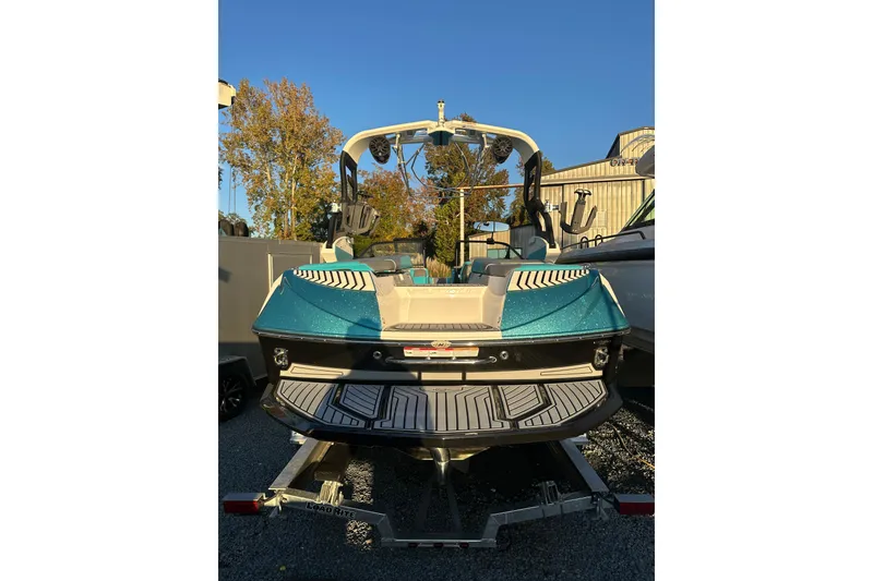 The Image of 2019 Nautique Super Air Nautique G21 boat on trailer, parked outside a metal building. - 2