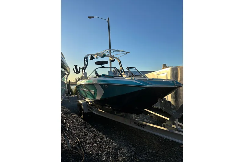 Slide: The Image of 2019 Nautique Super Air Nautique G21 boat with vibrant blue accents, docked outdoors. - 5