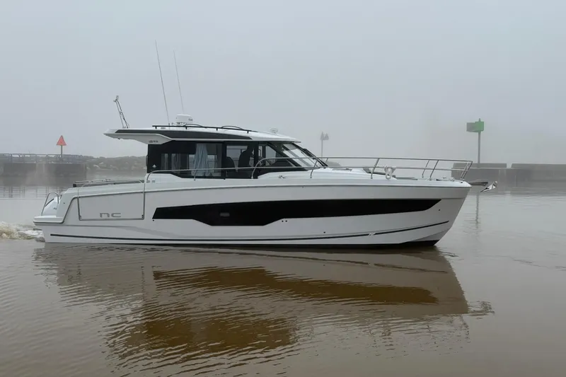 The Image of 2026 Jeanneau NC 1295 Coupe boat on calm water in a foggy setting. - 0