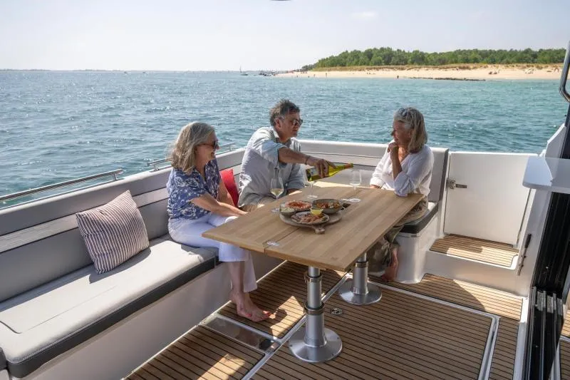 Slide: The Image of 2026 Jeanneau NC 1295 Coupe, people dining on deck, ocean view. - 15
