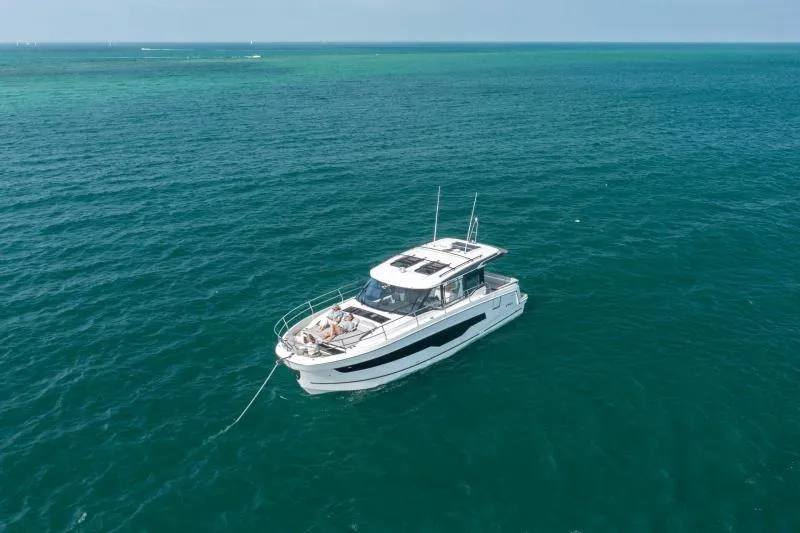 Slide: The Image of 2026 Jeanneau NC 1295 Coupe cruising on open sea under clear skies. - 2