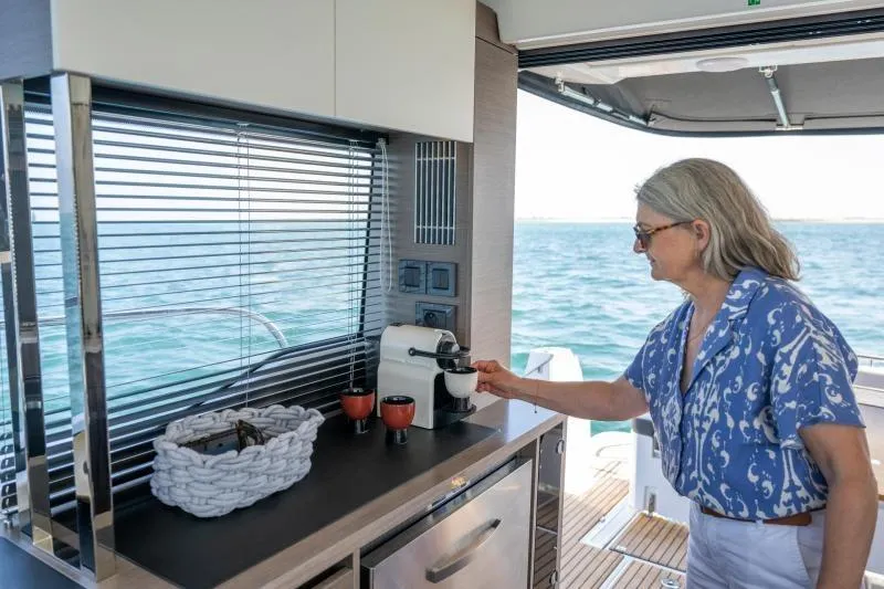 Slide: The Image of Woman making coffee on 2026 Jeanneau NC 1295 Coupe yacht kitchen. - 25