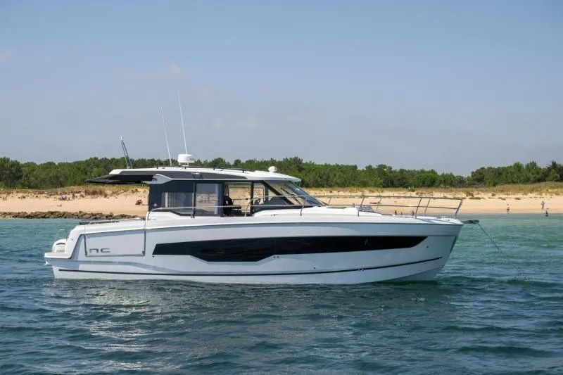 Slide: The Image of 2026 Jeanneau NC 1295 Coupe yacht cruising near a sandy beach. - 8