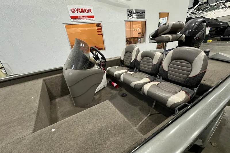 Slide: The Image of 2004 Bass Tracker 175 boat interior with seating and steering console in a showroom. - 4
