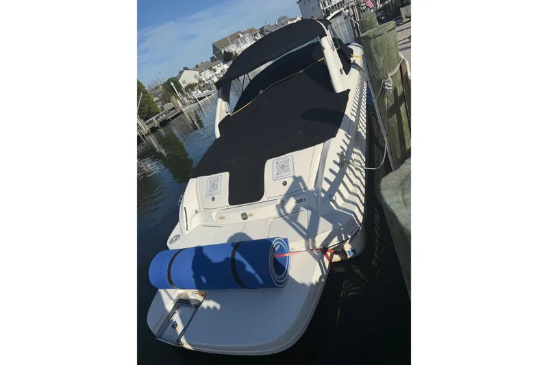 The Image of 2005 Sea Ray 290 SLX boat docked with black cover and blue mat. - 1