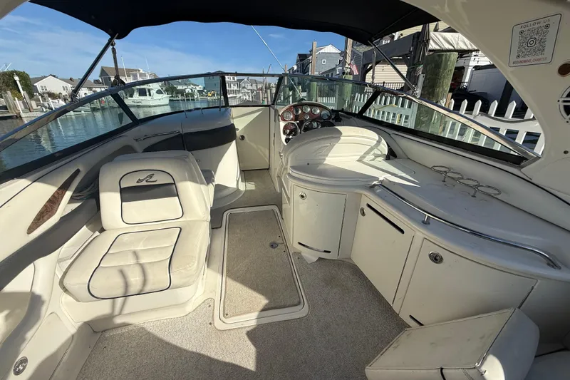 Slide: The Image of 2005 Sea Ray 290 SLX boat interior with seating and dashboard, docked at marina. - 6