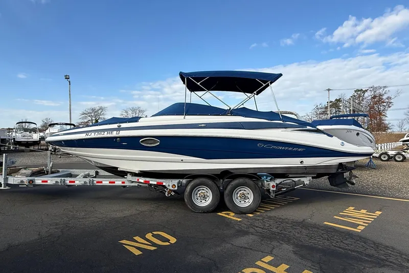 The Image of 2013 Crownline Eclipse E6 boat on trailer, blue and white, parked outdoors under clear sky. - 0