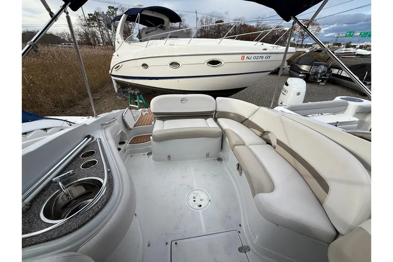 Slide: The Image of 2013 Crownline Eclipse E6 boat interior with seating and sink, parked near another boat. - 17
