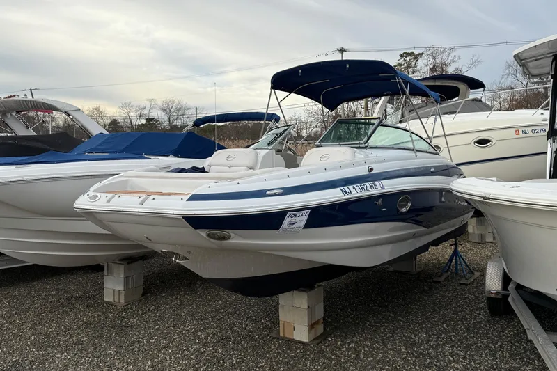 Slide: The Image of 2013 Crownline Eclipse E6 boat with blue and white exterior, displayed on blocks. - 2
