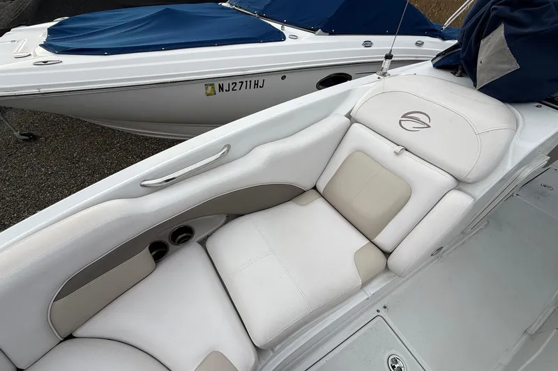 Slide: The Image of 2013 Crownline Eclipse E6 boat with white and beige seating, docked beside another boat. - 20