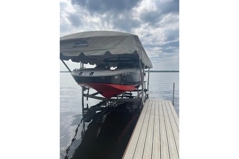 The Image of 2017 Four Winns HD220 RS boat in storage, featuring sleek black and red design. - 0