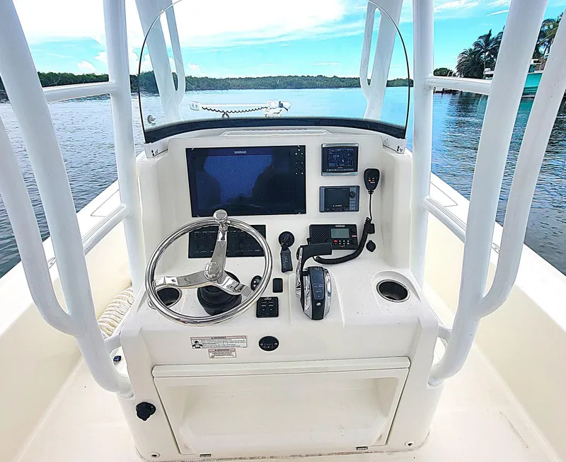 Slide: The Image of 2017 SeaVee 270Z boat console with steering wheel, navigation screens, and controls on calm water. - 13