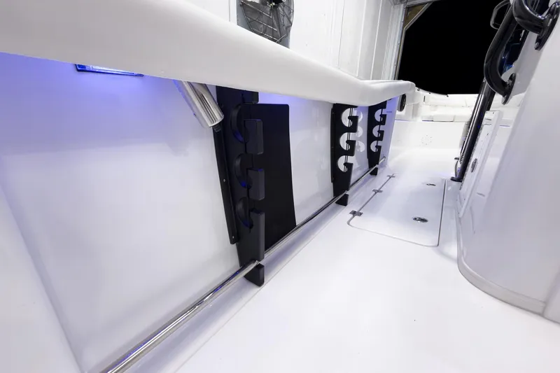Slide: The Image of 2026 Tidewater 272 CC Adventure boat interior with rod holders and blue LED lighting. - 33