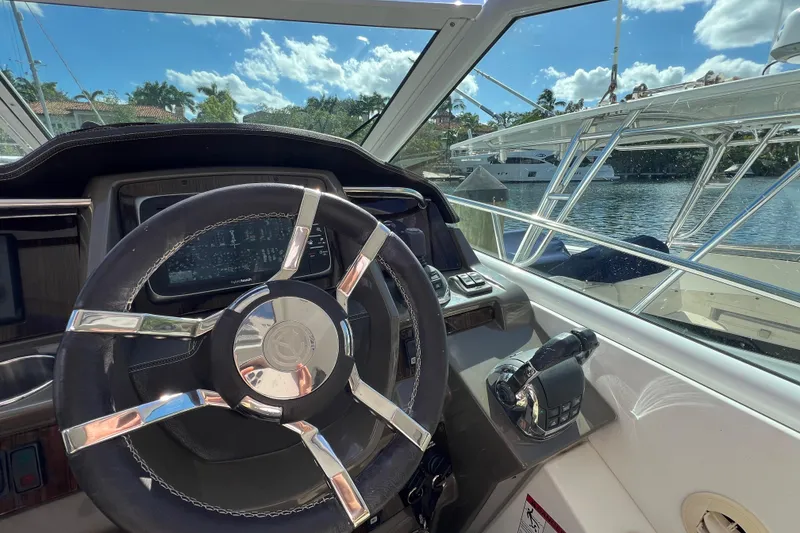 Slide: The Image of Helm of 2013 Cruisers Yachts 380 Express with steering wheel and controls, docked by water. - 13