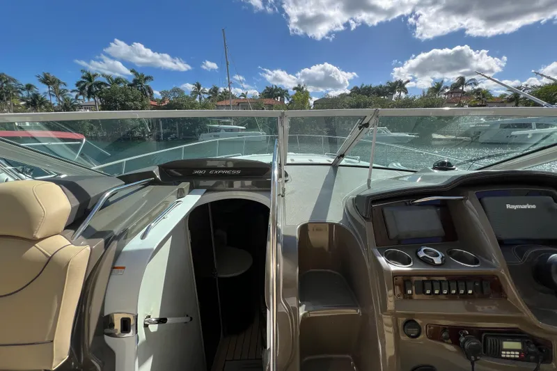 Slide: The Image of 2013 Cruisers Yachts 380 Express cockpit with navigation controls, docked by palm trees. - 15