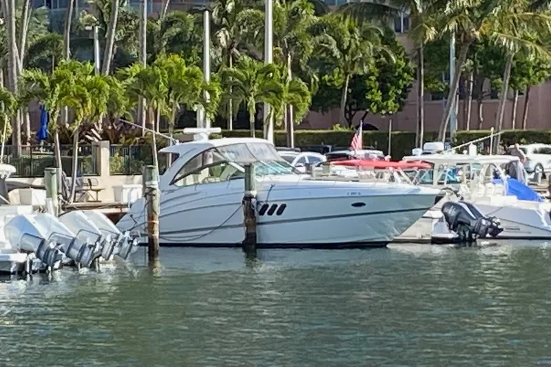 Slide: The Image of 2013 Cruisers Yachts 380 Express docked at a marina with palm trees. - 2