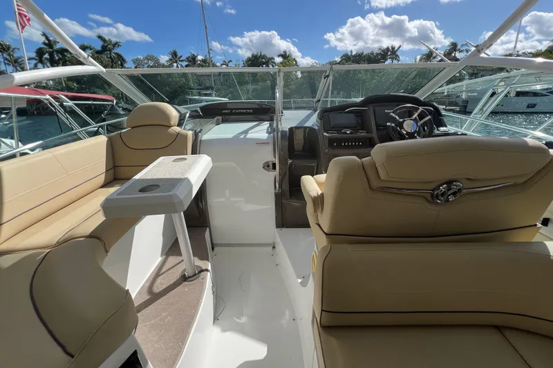 Slide: The Image of 2013 Cruisers Yachts 380 Express interior with beige seating and helm, under sunny skies. - 7