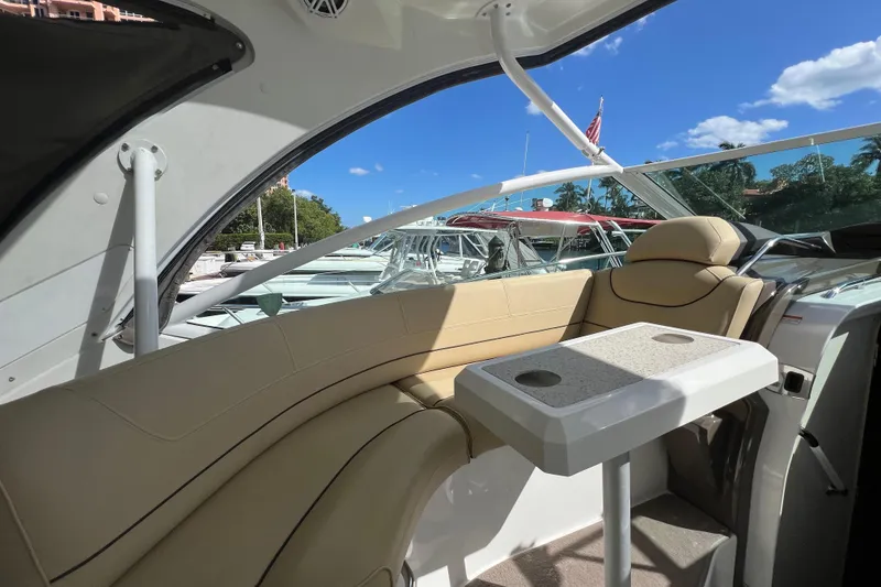 Slide: The Image of 2013 Cruisers Yachts 380 Express interior with seating and table, docked under blue sky. - 9