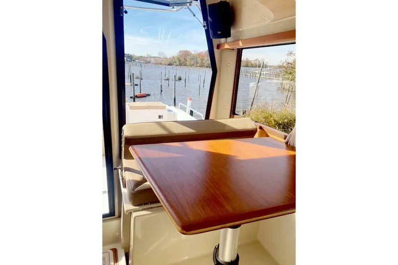 Slide: The Image of Interior view of 2021 Ranger Tugs R-25 with wooden table and scenic water backdrop. - 17