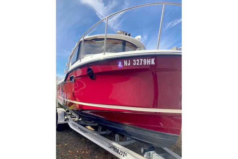 Slide: The Image of 2021 Ranger Tugs R-25 boat in vibrant red on a trailer, clear sky background. - 2
