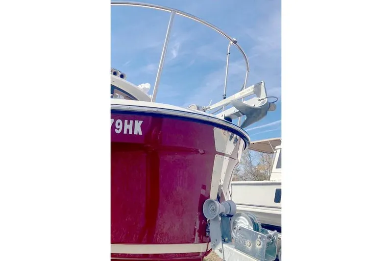 Slide: The Image of 2021 Ranger Tugs R-25 boat with red hull and visible anchor, under clear blue sky. - 3