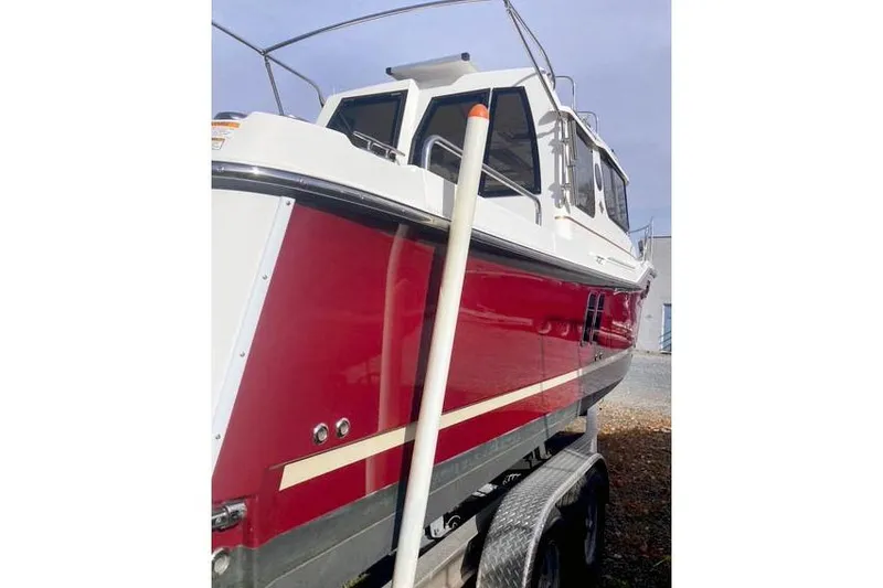 Slide: The Image of 2021 Ranger Tugs R-25 boat with red hull on trailer, side view. - 4