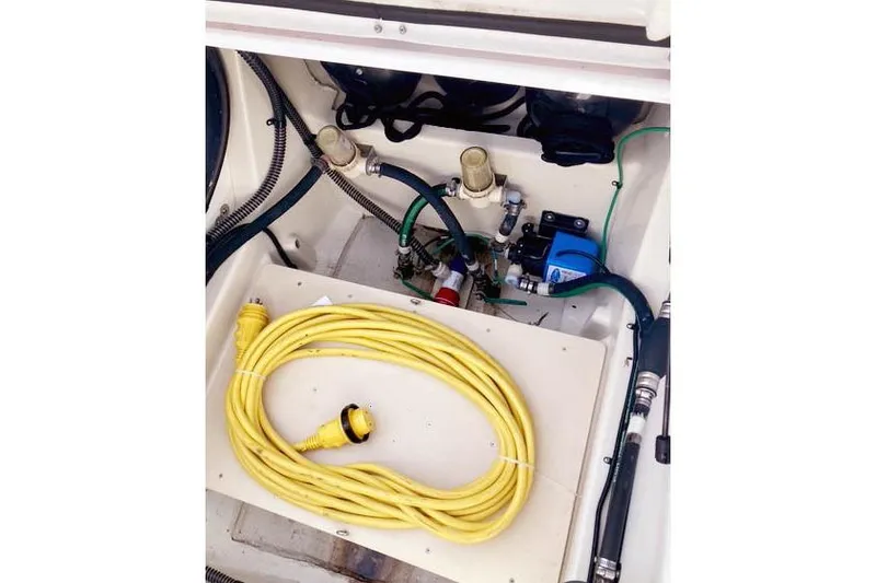 Slide: The Image of 2021 Ranger Tugs R-25 boat compartment with yellow power cable and plumbing components. - 41