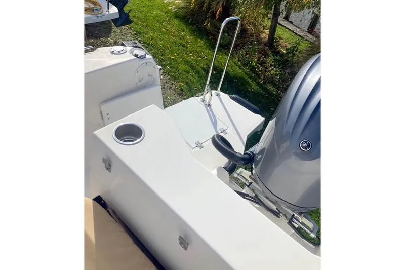 Slide: The Image of 2021 Ranger Tugs R-25 boat stern with motor and cup holder, outdoor setting. - 45