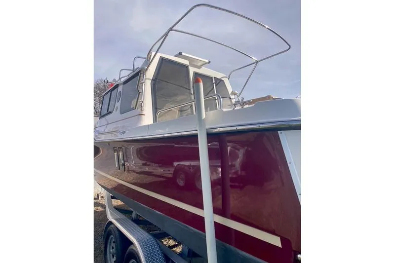 Slide: The Image of 2021 Ranger Tugs R-25 boat with red hull on a trailer, side view. - 5