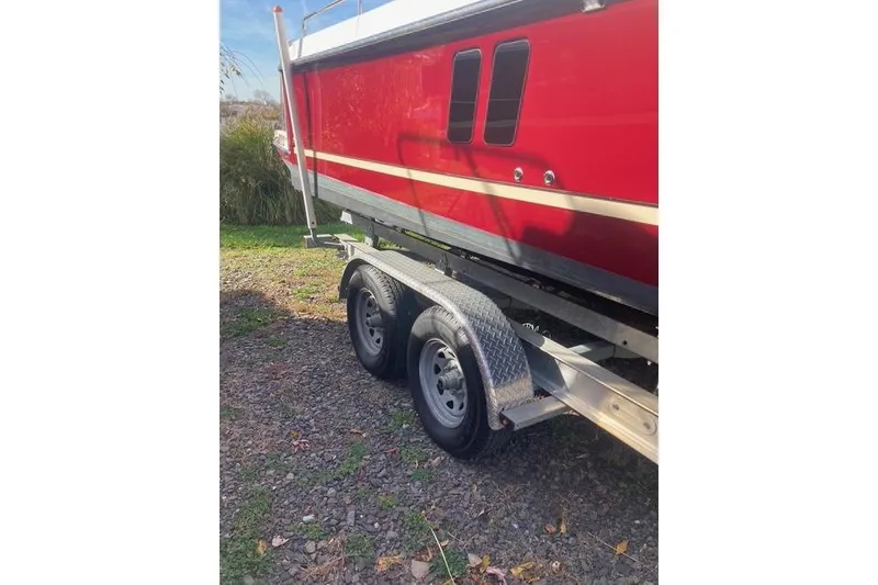 Slide: The Image of Red 2021 Ranger Tugs R-25 boat on trailer, parked on gravel. - 7
