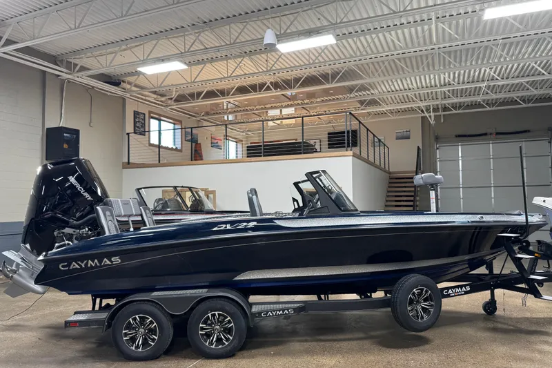 The Image of 2026 Caymas DV 22 boat in showroom, sleek design with dual console and powerful outboard motor. - 0