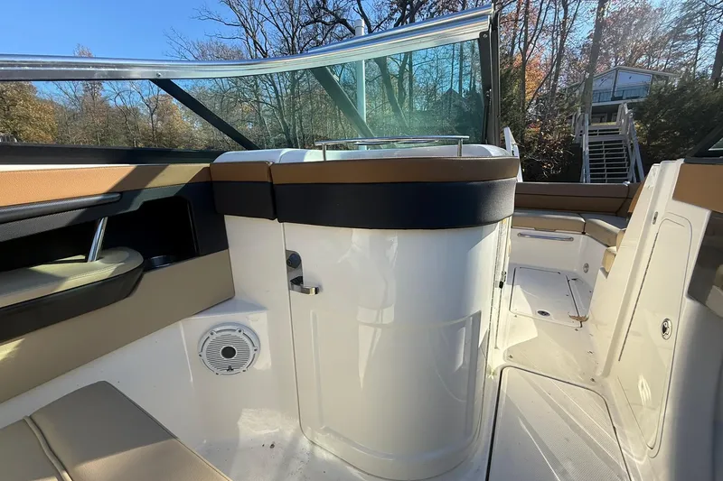 Slide: The Image of 2015 Sea Ray 240 Sundeck interior with seating and speaker, surrounded by trees. - 12