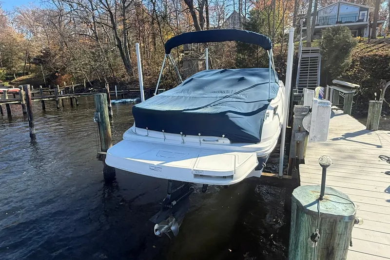 Slide: The Image of 2015 Sea Ray 240 Sundeck boat docked with cover, surrounded by autumn trees. - 3
