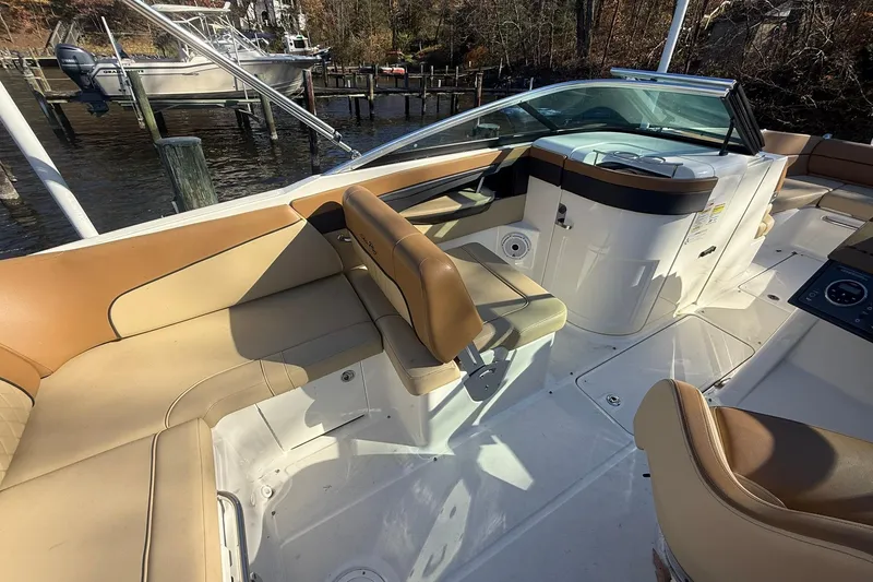 Slide: The Image of 2015 Sea Ray 240 Sundeck interior with tan seating and helm, docked by the water. - 9
