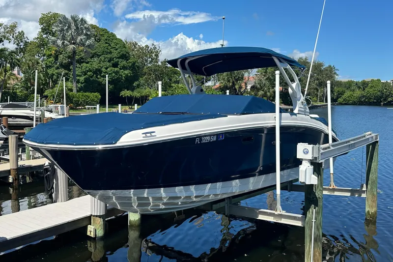 Slide: The Image of 2019 Sea Ray SDX 270 Outboard boat docked on a lift by a scenic river. - 0