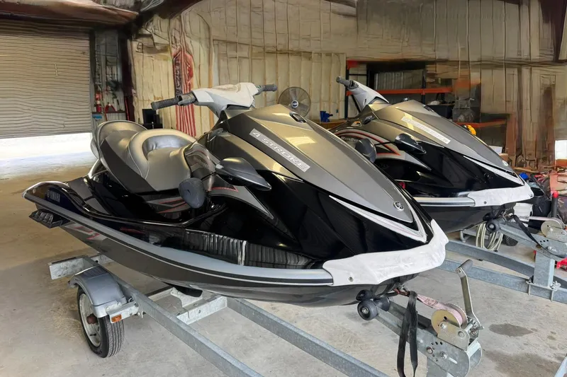 The Image of 2007 Yamaha WaveRunner VX Cruiser jet skis on trailers in a garage. - 1