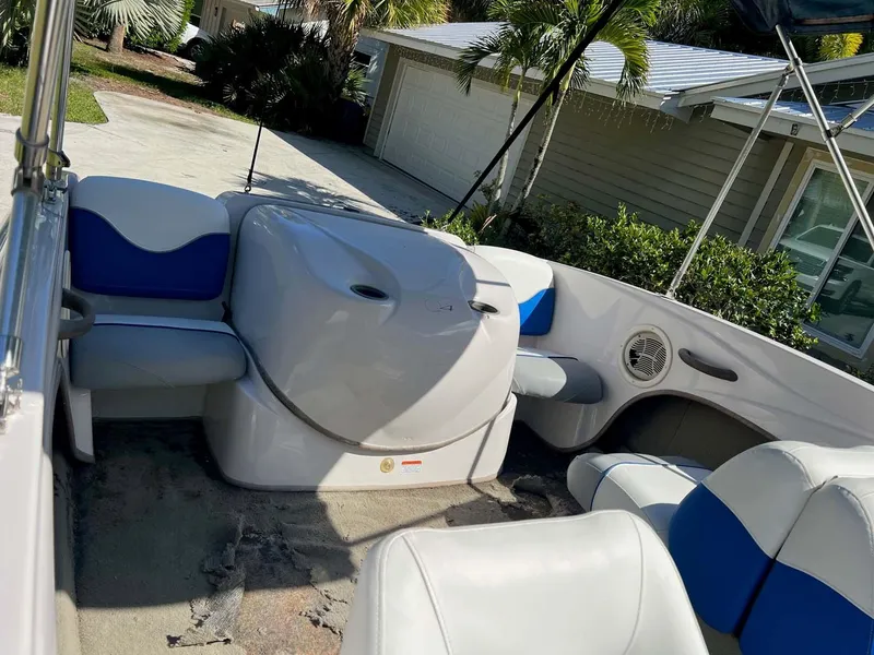 Slide: The Image of 2005 Tahoe T18 Ski Boat interior with blue and white seating, parked near a house. - 15
