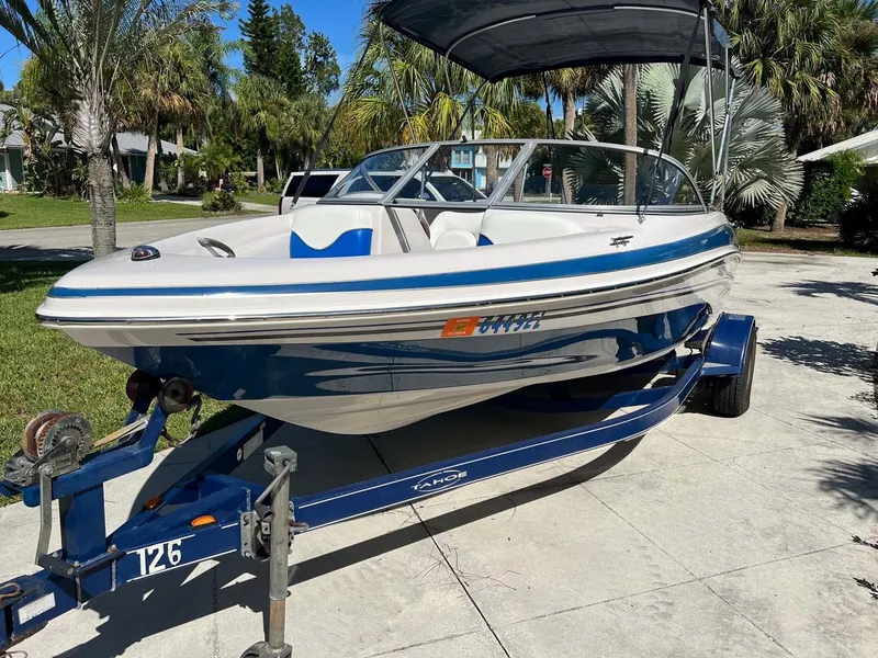 Slide: The Image of 2005 Tahoe T18 Ski Boat on trailer, parked outdoors, surrounded by palm trees. - 19