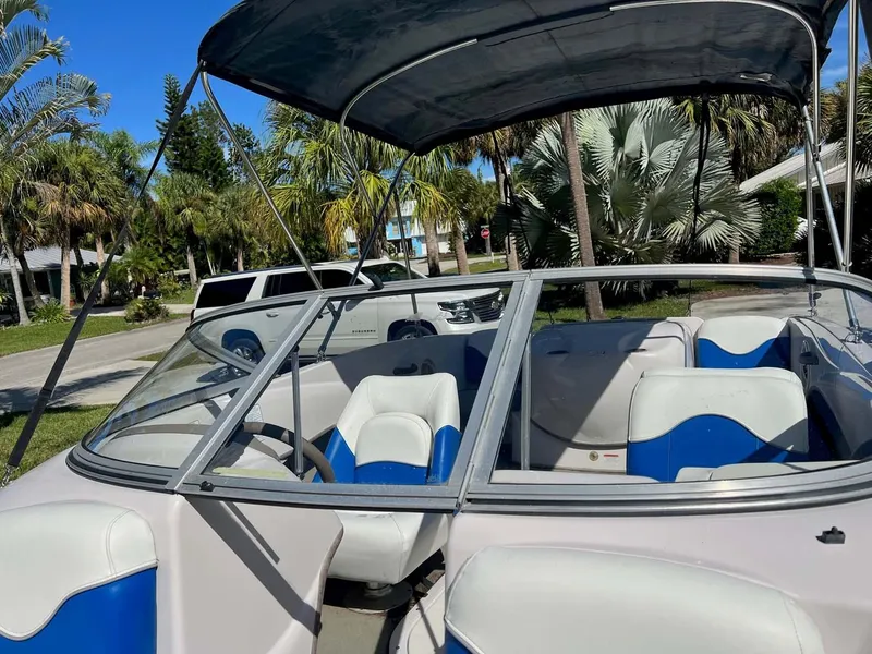 Slide: The Image of 2005 Tahoe T18 Ski Boat with blue and white seating, parked near palm trees. - 6