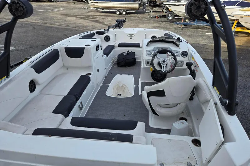 Slide: The Image of 2018 Tahoe 2150 boat interior with seating, steering wheel, and dashboard in a marina setting. - 10