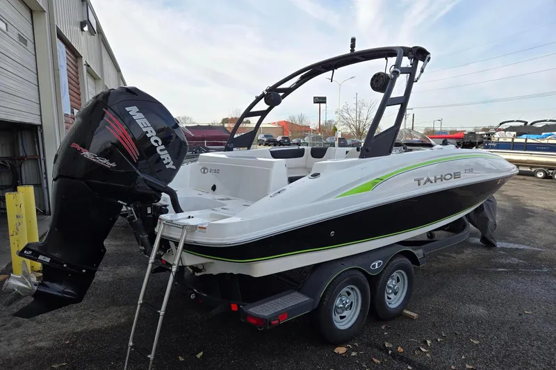 Slide: The Image of 2018 Tahoe 2150 boat with Mercury engine on a trailer, parked outdoors. - 2
