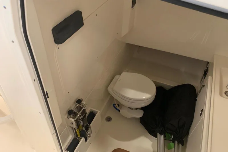 Slide: The Image of 2019 Boston Whaler 330 Outrage boat interior with compact marine toilet and storage area. - 13